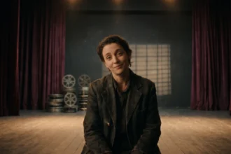 An actor on a dimly lit stage looking directly into the camera, representing the concept of breaking the fourth wall in film and theatre.