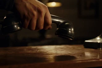 A hand lowering a telephone handset onto a desk in a dramatic, cinematic lighting setting