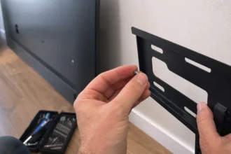 Hands holding a screw next to a TV wall mount bracket before installation