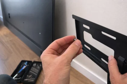 Hands holding a screw next to a TV wall mount bracket before installation
